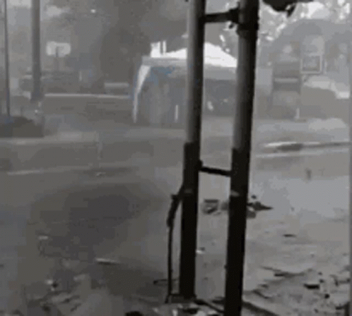 Black and White Photo of Person Standing Next to Pole in Street