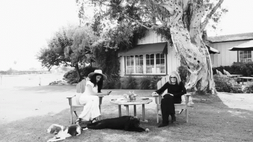 Black and White Photo of Two Women With Dogs in Front of a House