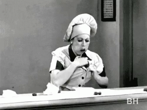Black and White Photo of Woman in Chef Hat Eating