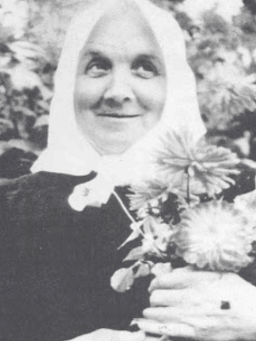 Black And White Photo Of Woman In White Head Scarf Holding Flowers GIF