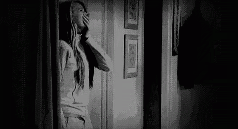 Black and White Photo of Woman Looking Out Door in Hallway