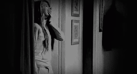 Black and White Photo of Woman Looking Out Doorway
