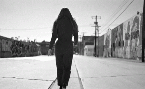 Black And White Woman Walking Past Graffiti Wall GIF