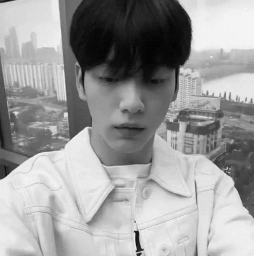 Black And White Young Man In White Jacket Looking Out Window GIF