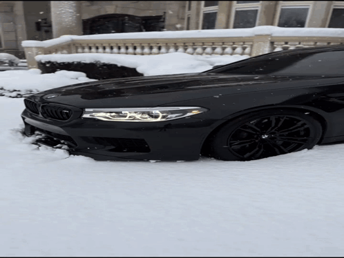Black BMW Stuck In Snow In Front Of Building GIF