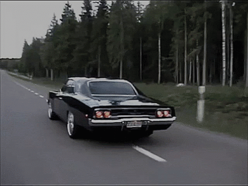 Black Car Driving Down Road With Trees