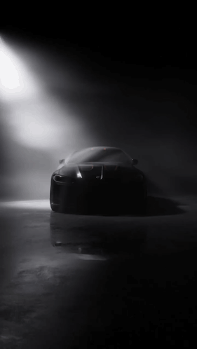 Black Car Silhouetted Against Spotlight in Dark