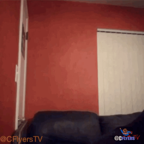 Black Couch With Red Wall and Flyers TV Logo