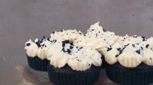 Black Cupcakes With White Frosting And Black Sprinkles On Top GIF