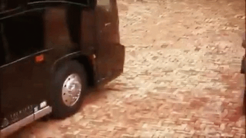 Black Limousine Driving on Cobblestone Street