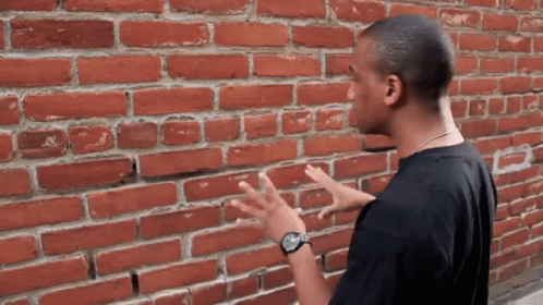 Black Shirt Man by Red Brick Wall