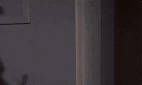 Blonde Girl Sneaks Through Door Opening GIF