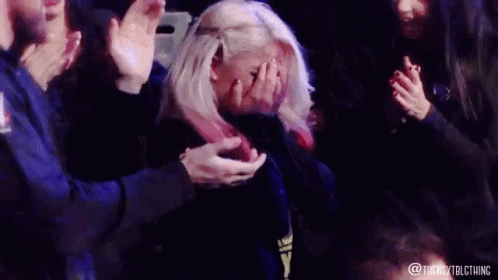 Blonde Woman Covering Face as Crowd Applauds