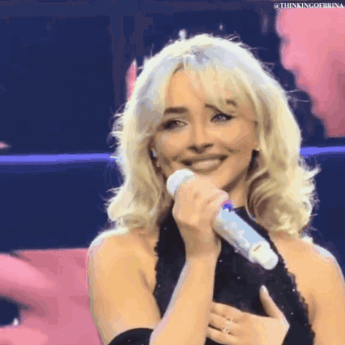 Blonde Woman in Black Dress Holding Microphone Smiling