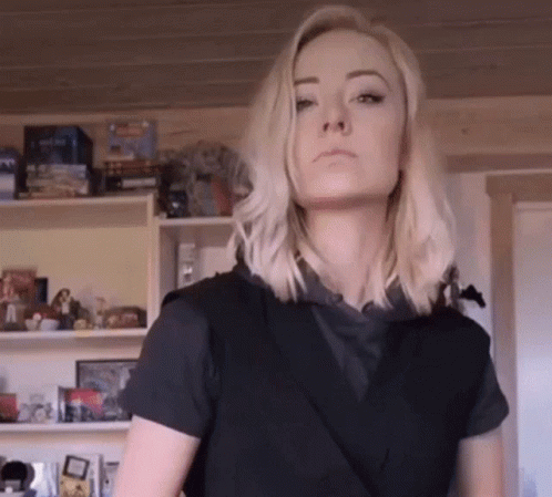 Blonde Woman In Black Shirt In Front Of Toy Shelf GIF