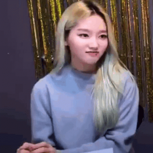 Blonde Woman in Blue Sweater Before Gold Curtain