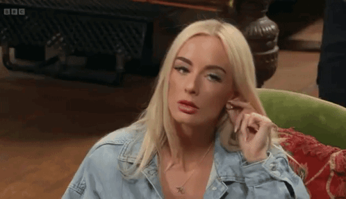 Blonde Woman In Denim Shirt Sitting In Green Chair GIF