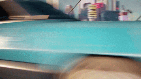 Blue Car Driving Down Street With City Skyline