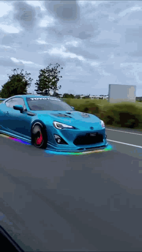 Blue Car With Toyota Logo Driving Down Road