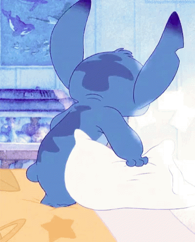Blue Cartoon Character Laying on Bed with White Pillow