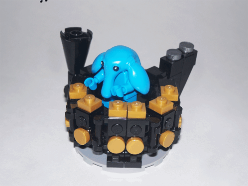 Blue Lego Figure Sitting on Black and Gold Block