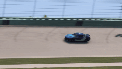 Blue Race Car Driving on Track with Green Fence
