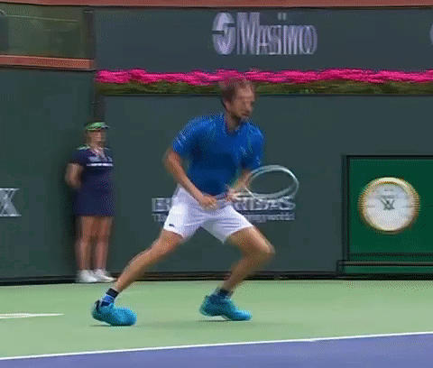 Blue Shirt Man Holding Tennis Racquet Masimo Sign