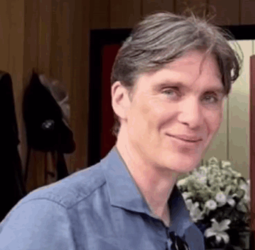 Blue Shirt Man Smiling With Vase Of Flowers GIF