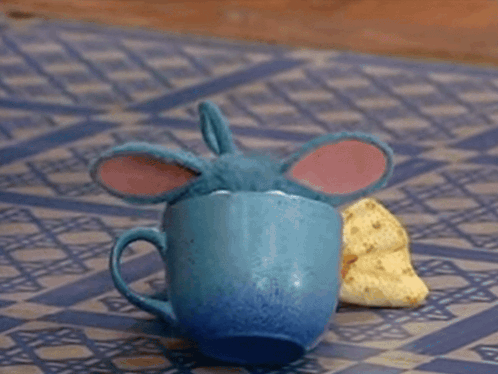 Blue Toy Sitting On Checkered Mat Eating Banana GIF
