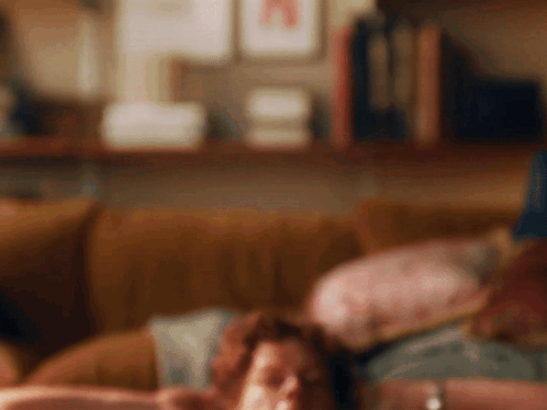 Blurry Person Laying On Couch With Bookshelf GIF