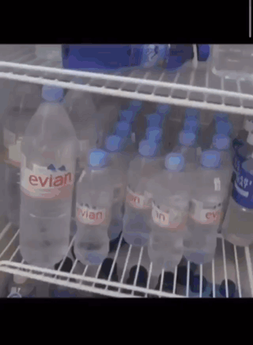Bottles Of Evian Water Are Lined Up On A Shelf GIF
