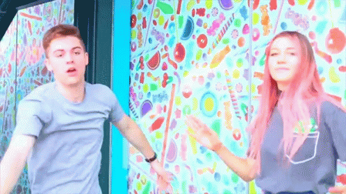 Boy and Girl With Pink Hair Dancing in Front of Candy Wall