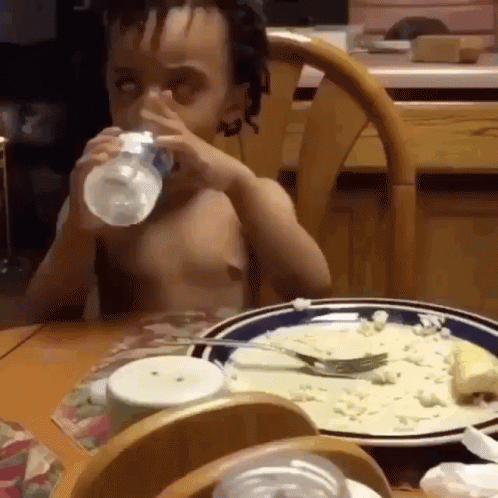 Boy Drinking Water from Bottle at Table with Food