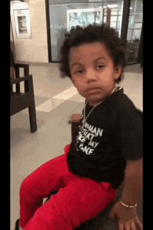 Boy in Black Shirt and Red Pants Sitting on Chair
