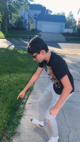 Boy in Black T-Shirt and Grey Sweatpants Pointing