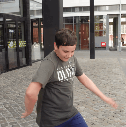 Boy in Grey Aeropostale Shirt Dancing on Cobblestone Street