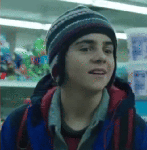 Boy in Hat and Blue Jacket in Front of Store Shelf
