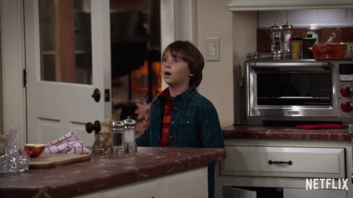 Boy In Kitchen With Netflix Logo On Counter GIF