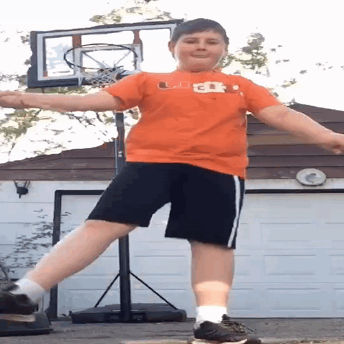 Boy in Orange Shirt and Black Shorts at Basketball Net
