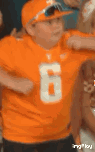 Boy in Orange Shirt and Hat Number 6