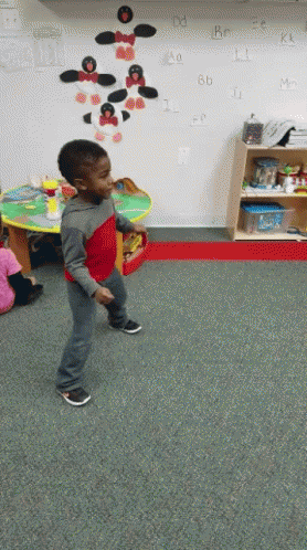 Boy in Red Shirt Dancing in Front of Alphabet Wall