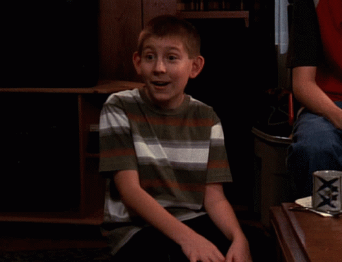 Boy in Striped Shirt Sitting in Front of XXX Can