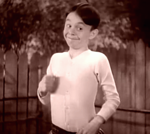 Boy in White Shirt Smiling at Fence