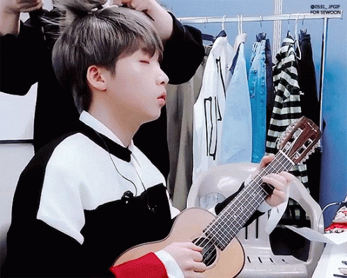 Boy Playing Guitar in Dressing Room Being Adjusted