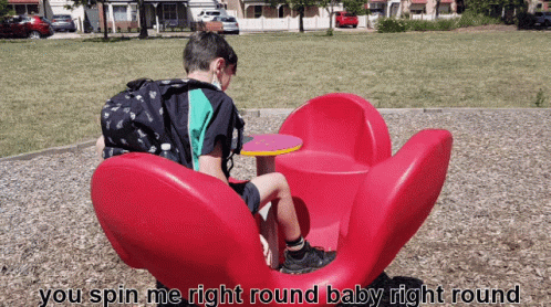 Boy Sitting on Red Flower Merry Go Round