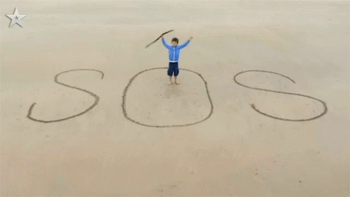 Boy Standing on Beach With SOS in Sand