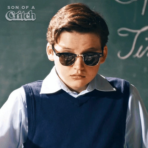 Boy Wearing Sunglasses in Front of Blackboard