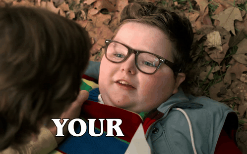 Boy With Glasses Laying on Ground Saying Your