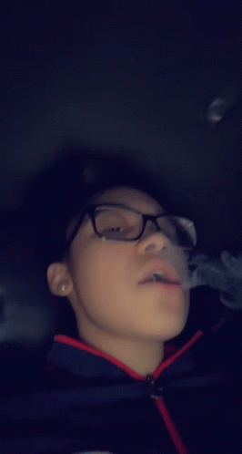 Boy With Glasses Smoking Cigarette in Dark Room
