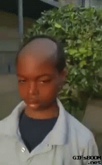 Boy with Shaved Head in Front of Bush
